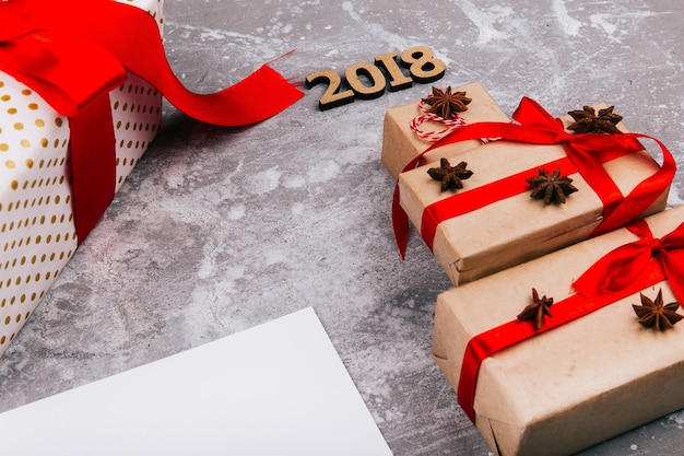 クリスマスツリーは、赤い現在のボックスと番号2018で作られた空白のカードの上に灰色の床に横たわっている