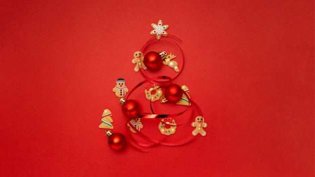 Christmas tree made with christmas cookies and christmas balls on red table