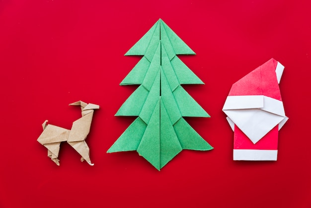 Christmas tree; reindeer; santa claus paper origami on red backdrop