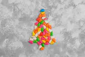 Free photo christmas tree shaped sparkle candies on a gray table. top view, flat lay