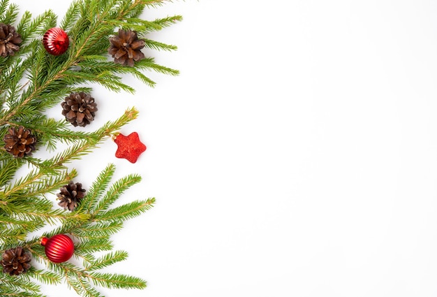 Рождественский белый фон с еловой веткой, шишками и еловыми игрушками, плоской планировкой, видом сверху, копией пространства Premium Фотографии
