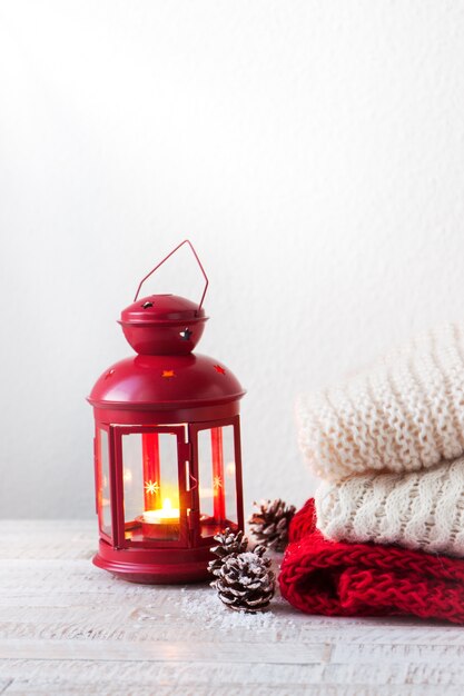 Christmas or winter home concept with lantern, fir cones, snow and warm wear, with copy space