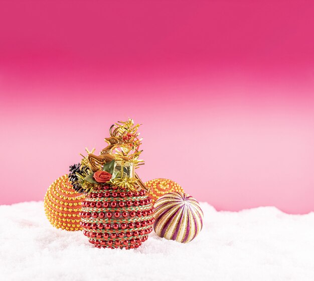 ピンクの背景に雪の上のカラフルなおもちゃとクリスマス