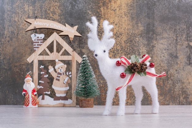 Christmas wooden decoration and deer toy on white surface.