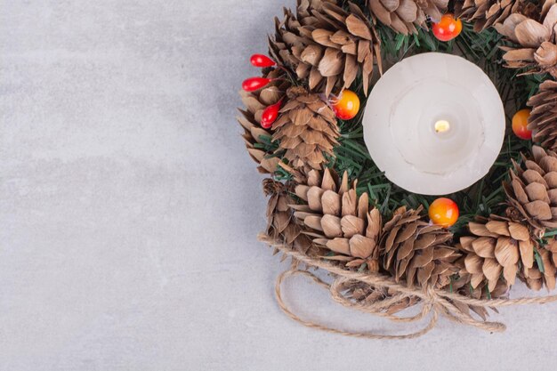 Christmas wreath and candle on white table.