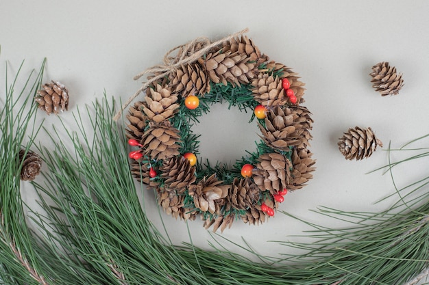 Christmas wreath and pinecones on beige surface Free Photo