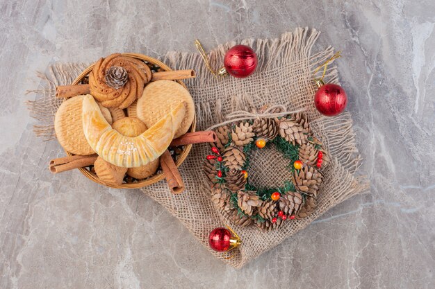 Christmas wreath, tree decorations and a pastry basket on marble.