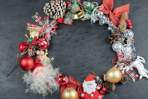 Christmas wreath with festive ornaments on dark surface