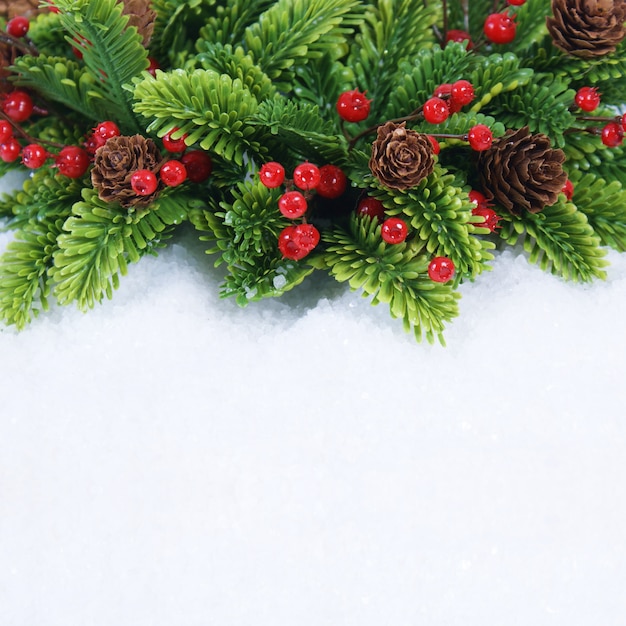 雪の中に松の木とベリーが飾られたクリスマスの花輪