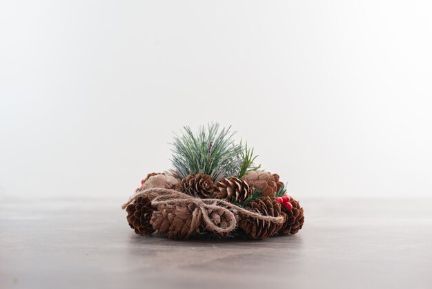 Christmas wreath with red beads and cones on marble.