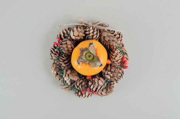 A Christmas wreath with a whole fresh persimmon .