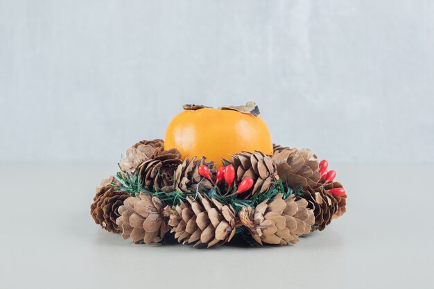 A Christmas wreath with a whole fresh persimmon .