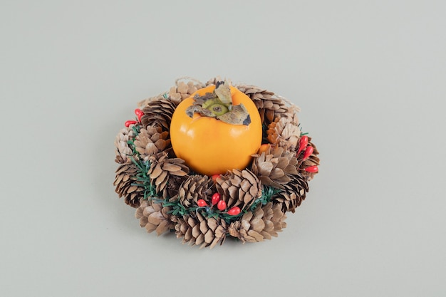 A Christmas wreath with a whole fresh persimmon .