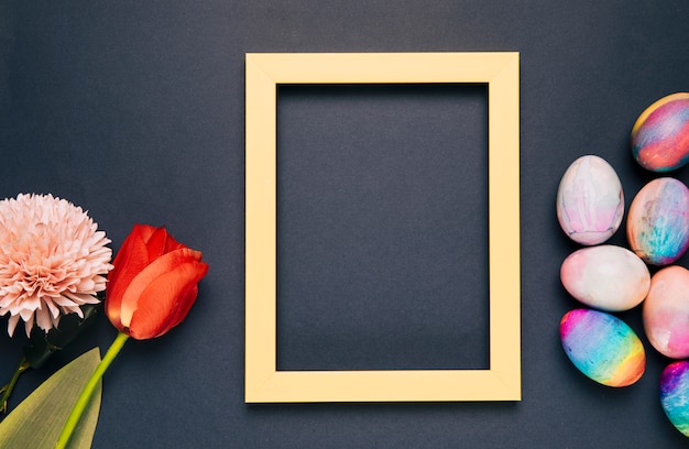 Chrysanthemum; tulip and painted easter eggs with yellow empty frame on black background