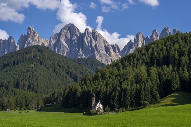 Church in a green landscape surrounded by rocky mountains in Funes Valley,  St. Italy