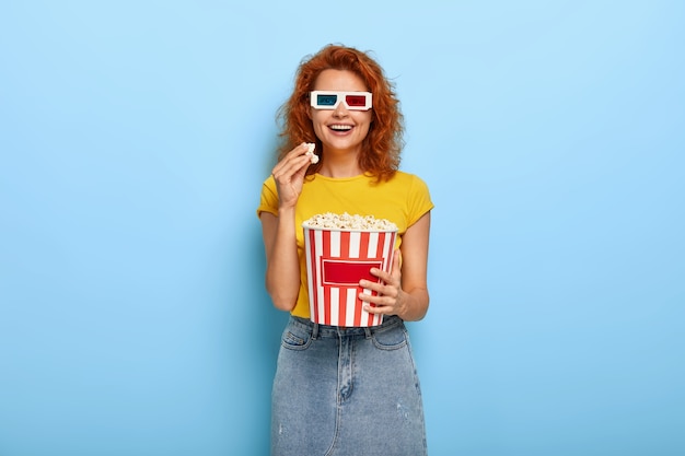 映画館の日と自由時間の概念。若い楽観的な赤い髪の幸せな女性は面白い映画を見ながら楽しんでいます