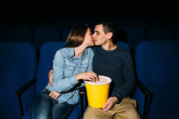映画館の日。映画館でロマンチックな映画を見ながらキスしている若い美しいカップル。