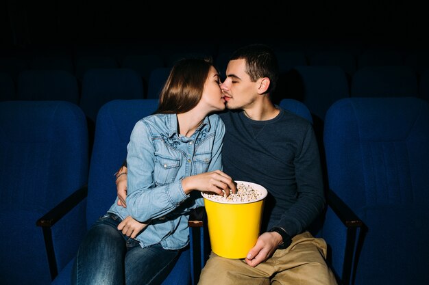  Cinema day. Young beautiful couple kissing while watching romantic movie at cinema.