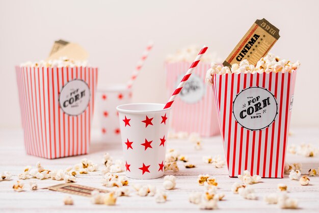 Cinema ticket in the popcorns box with drinking glass and straw on wooden table