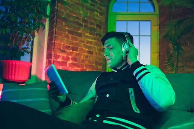 Cinematic portrait of handsome young man in neon lighted room, stylish musician