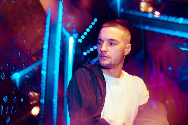 Cinematic portrait of handsome young man in neon lighted room, stylish musician