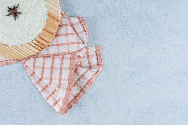 Cinnamon on oat porridge in wooden plate on towel on marble.