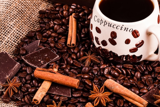 Cinnamon and other species lie on coffee beans before a cup