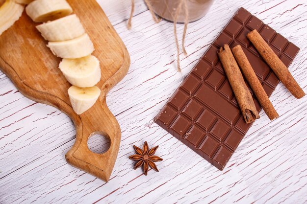cinnamon sticks lies on bar of chocolate and banana slices lies