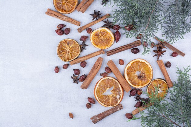 Cinnamon sticks, rosehips and dried orange slices on surface.