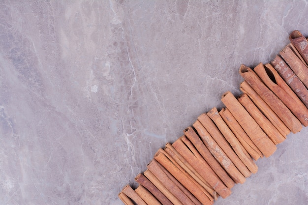 Free photo cinnamon sticks in a row on the stone surface