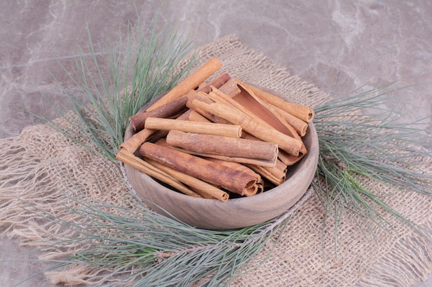 Foto gratuita bastoncini di cannella in una tazza di legno con ramo di quercia intorno
