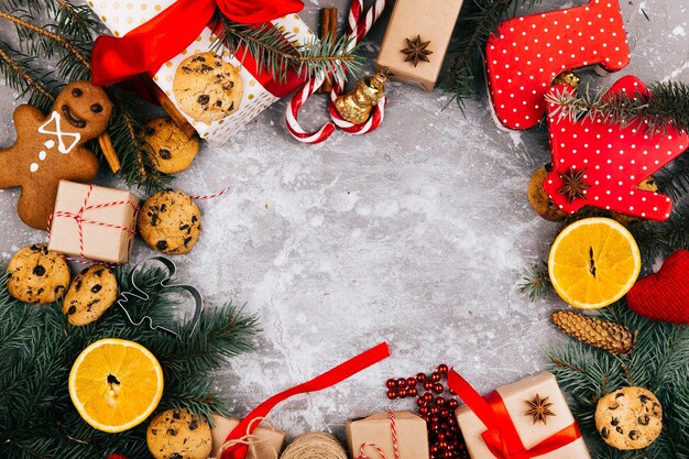 Circle made of oranges, cookies, fir branches and red present boxes