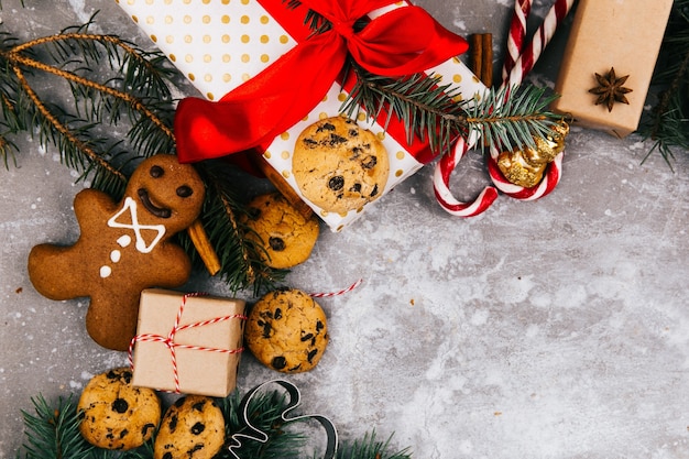 Circle made of oranges, cookies, fir branches and red present boxes