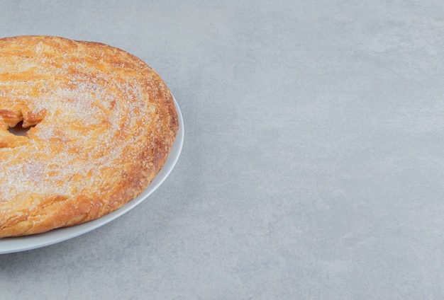 Circle pastry decorated with powder on white plate. 