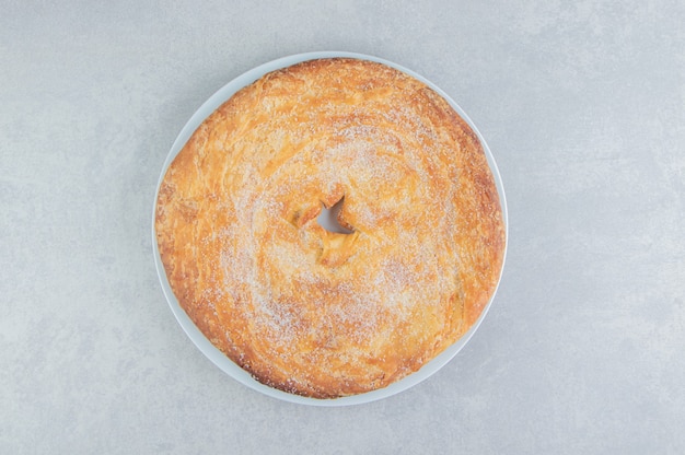 Circle pastry decorated with powder on white plate. 