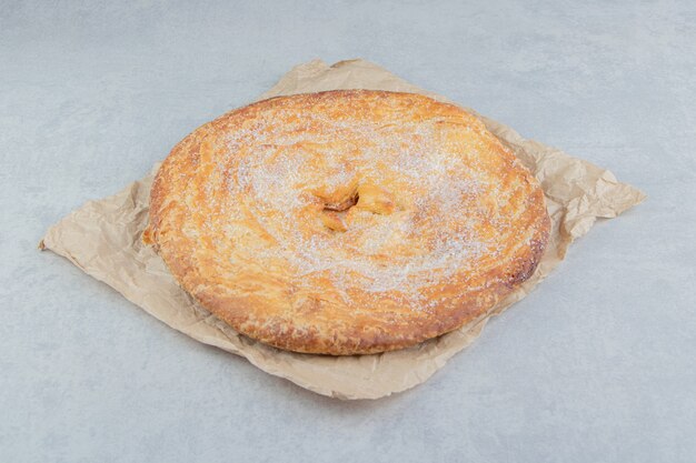 Circle pastry decorated with white powder on sheet. 