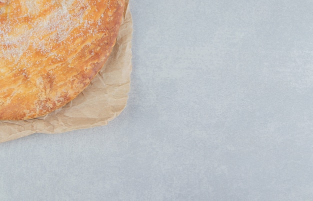 Circle pastry decorated with white powder on sheet. 