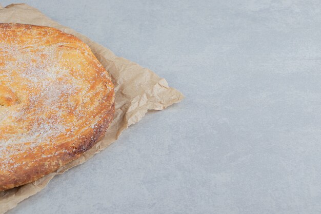 Circle pastry decorated with white powder on sheet. 