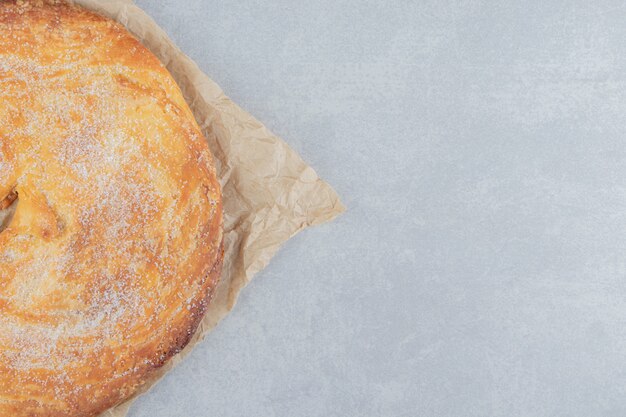 Circle pastry decorated with white powder on sheet.