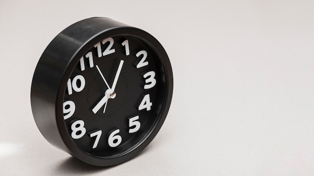Circular black alarm clock against gray background