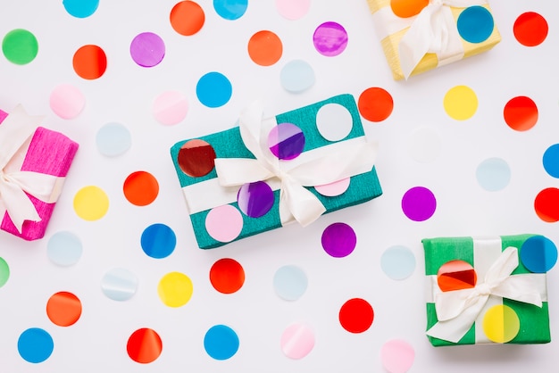 Free photo circular colorful confetti on gift boxes against white background