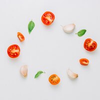 Foto gratuita cornice circolare realizzata con pomodorini; chiodi di garofano di aglio e basilico su sfondo bianco