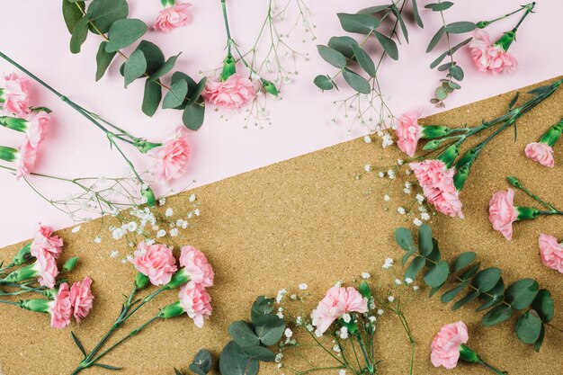 Circular frame made with gypsophila and pink carnation flowers on dual pink and cardboard backdrop