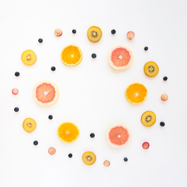 Free photo circular frame made with orange; grapes; kiwi; grapefruit and blueberries on white background