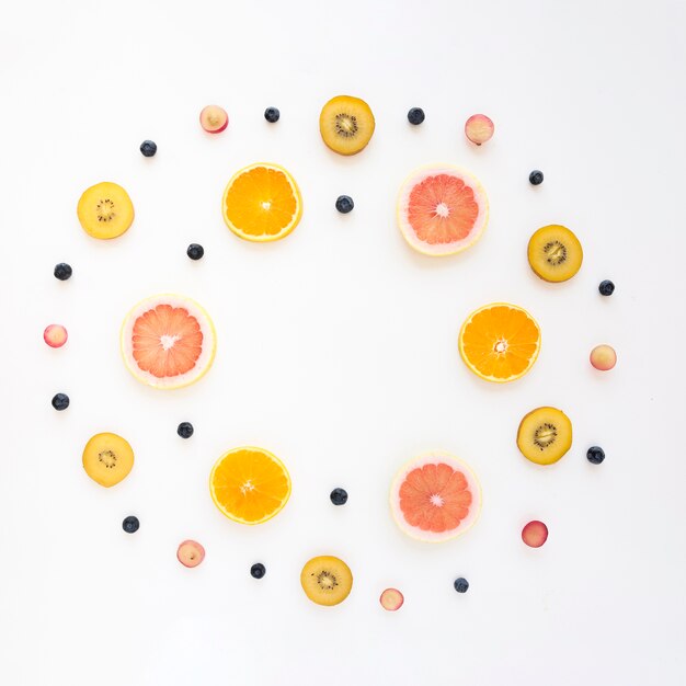 주황색으로 만든 원형 프레임; 포도; 키위; 자몽과 흰색 배경에 블루 베리