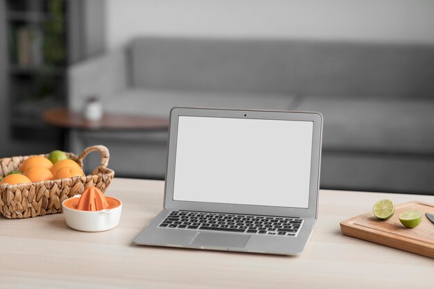 Цитрусовые и ноутбук с пустым экраном на деревянном столе
