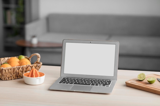 Citrus fruit and laptop with blank screen on a wooden table