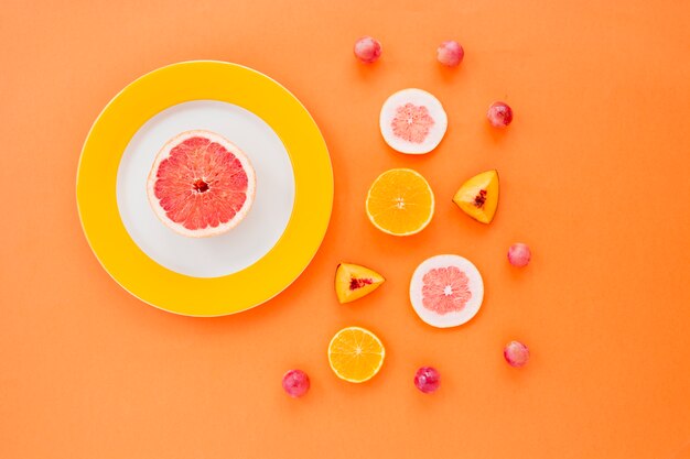 Citrus fruit; peach slices and grapes on an orange background