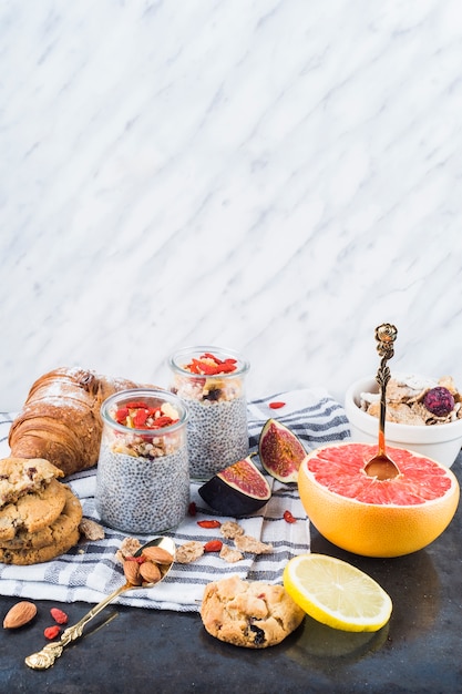 Citrus fruit slices; healthy smoothie with backed cookies and croissant on napkin