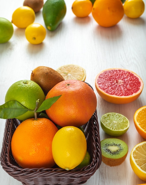 柑橘系の果物カラフルなアボカドレモンキウイオレンジテーブルの上のバスケットに